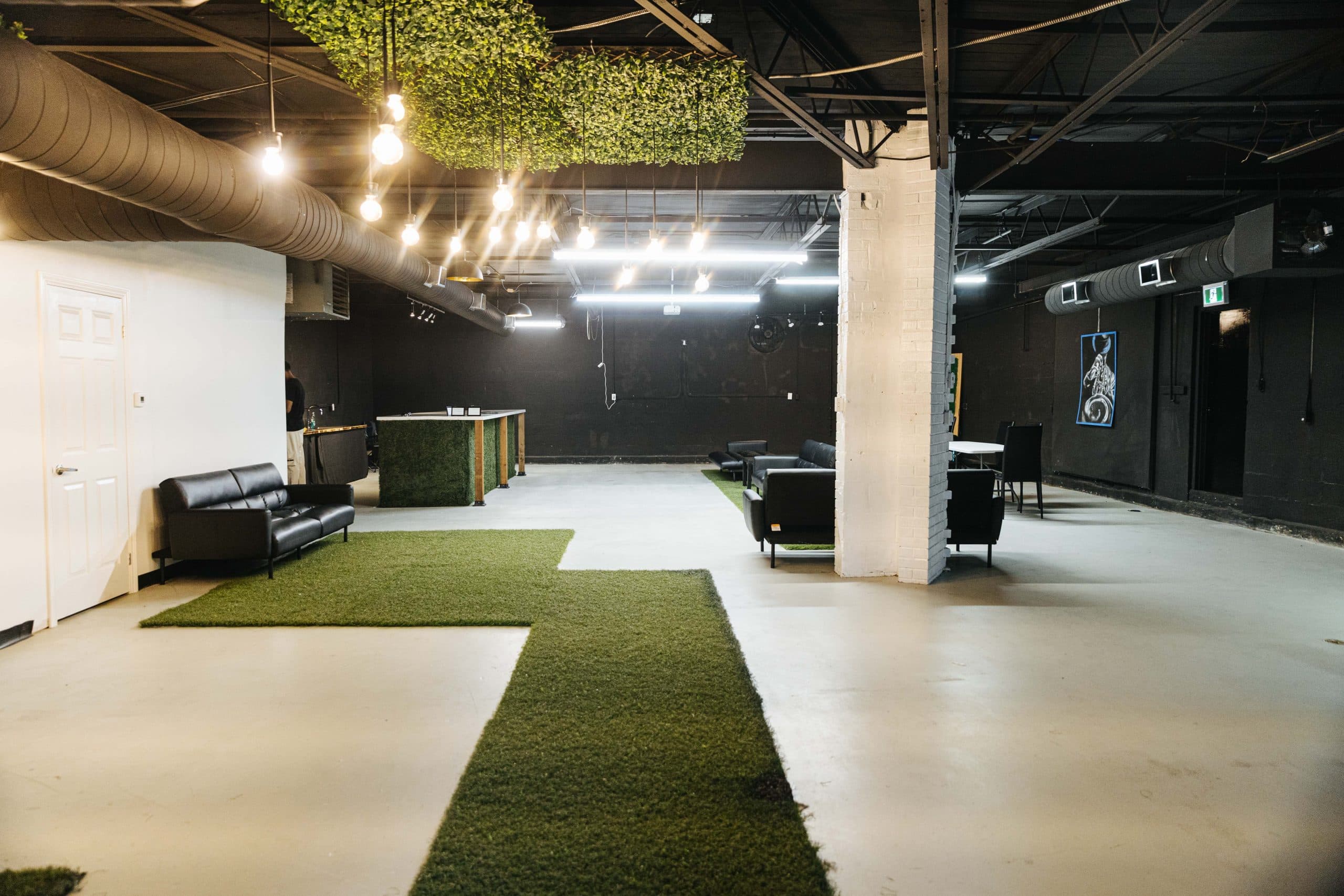 A wide view of the main room at Half Note, showing hanging greenery, pendant lighting and the white brick column.