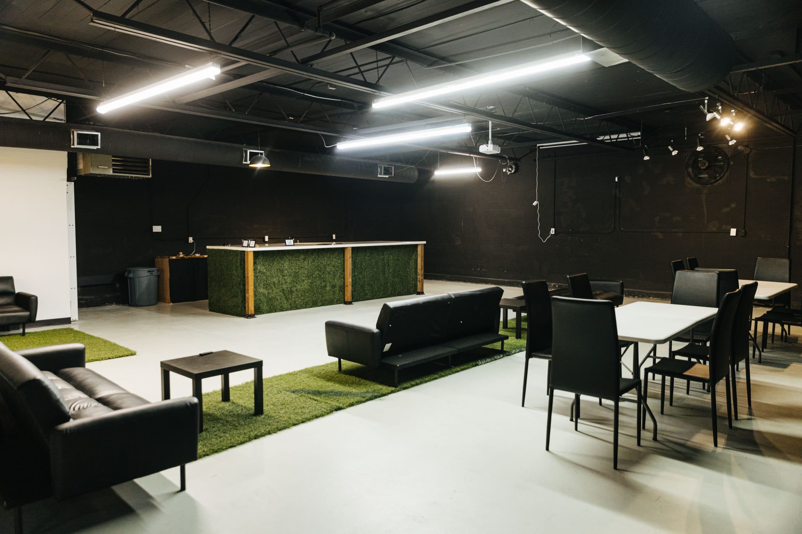 Lounge seating on turf runners and a table set with black chairs, in front of Half Note's turf-fronted presentation bar.